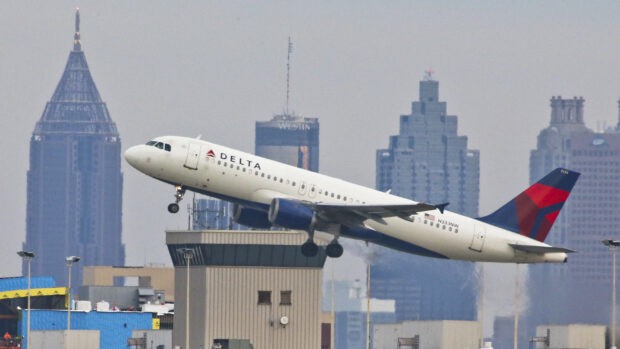 A Delta Air Lines airplane is taking off with city buildings in the background, 2K Desktop Wallpaper