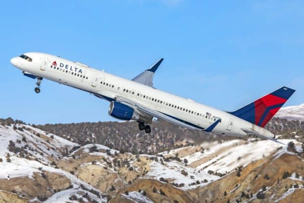 A Delta Air Lines plane is ascending over snowy mountains under a clear blue sky, 2K Desktop Wallpaper