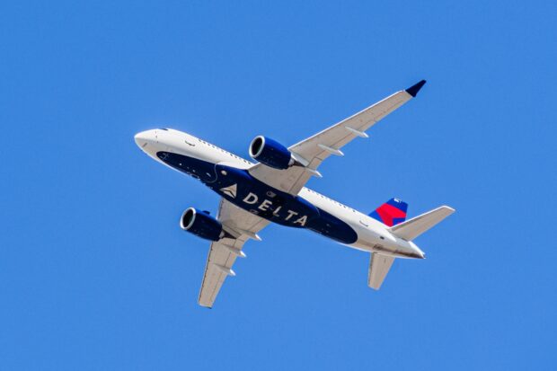 A Delta Air Lines plane is captured flying high against a clear blue sky, 2K Desktop Wallpaper