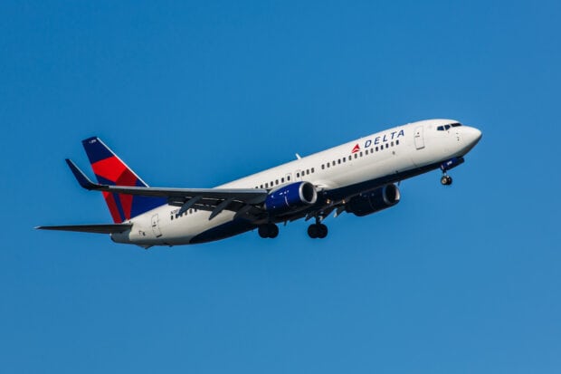 A Delta Air Lines plane is captured flying against a clear blue sky, HD Desktop Wallpaper
