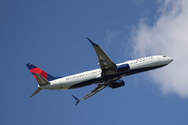 A Delta Air Lines airplane flies against a blue sky with white clouds, 2K Desktop Wallpaper
