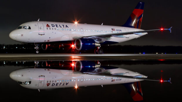 A Delta Air Lines plane is parked on the runway with its reflection visible on the wet surface at night, HD Desktop Wallpaper