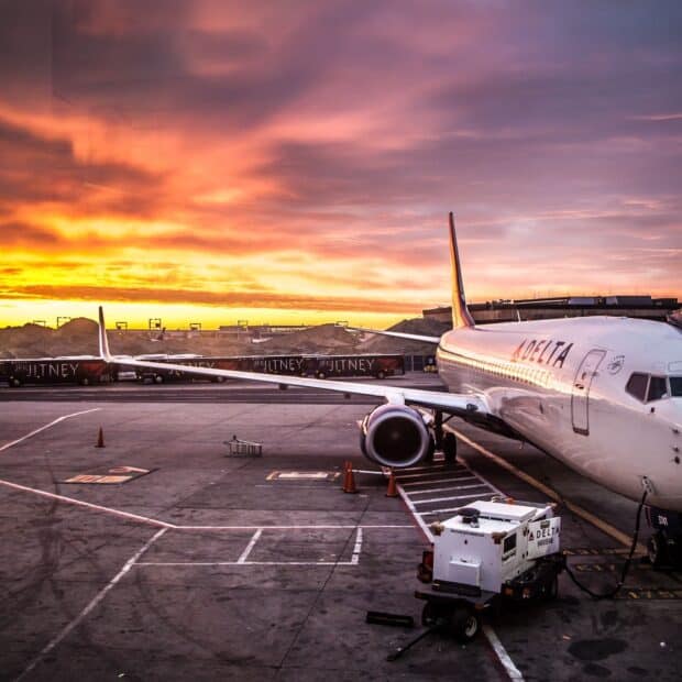 A Delta Air Lines plane is parked on the tarmac during a vibrant sunset sky, HD Desktop Wallpaper
