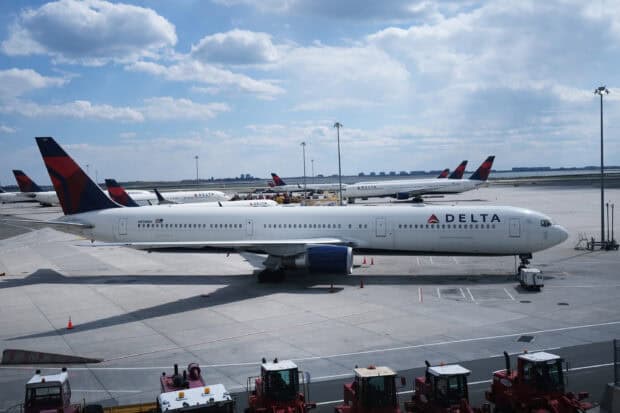 Several Delta Air Lines airplanes are parked on the airport runway under a partly cloudy sky, 2K Desktop Wallpaper