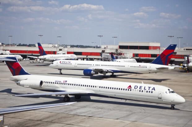 Several Delta Air Lines airplanes are parked and taxiing at the airport under a cloudy sky, HD Desktop Wallpaper