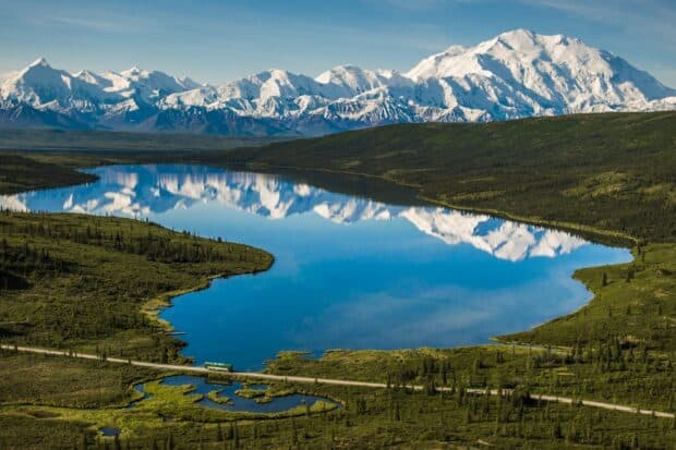 A clear lake reflects snow capped mountains in Denali National Park and Preserve, 2K Desktop Wallpaper