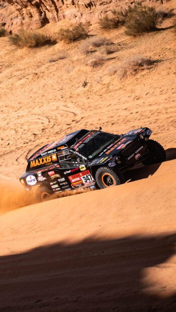A rally raid truck speeds across sandy dunes kicking up dust in the desert, HD Mobile Wallpaper