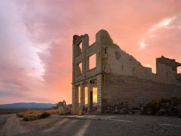 An abandoned building stands tall in a ghost town with a colorful sunset sky, HD Desktop Wallpaper