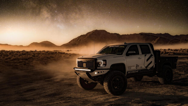 A rugged truck drives off road in the desert at night under a starry sky, 4K Desktop Wallpaper