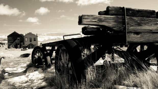 An old wooden wagon stands in an abandoned ghost town with old buildings in the background, HD Desktop Wallpaper