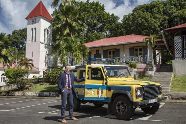 A man stands with a police vehicle outside a colonial building in Death In Paradise TV series, HD Desktop Wallpaper