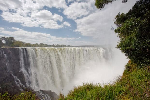 A scenic view of Devils Pool Zambia with lush greenery and cloudy sky, HD Desktop Wallpaper