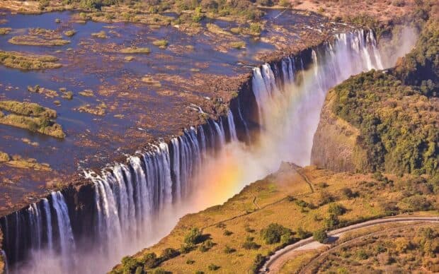 A stunning aerial view of Devils Pool Zambia with cascading water and a rainbow, HD Desktop Wallpaper