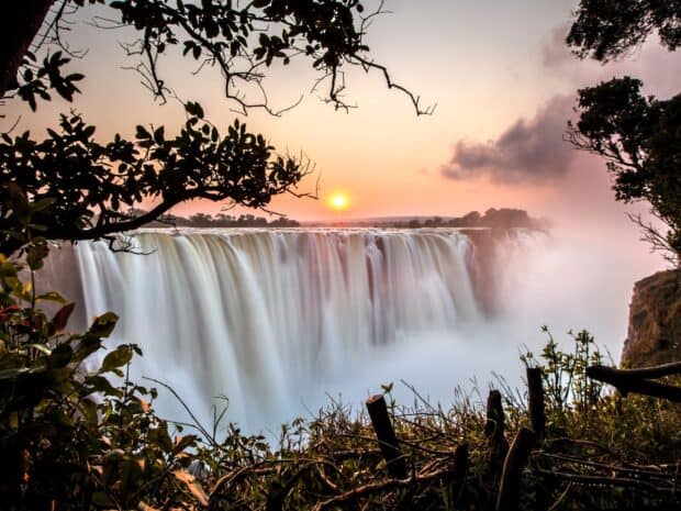 The Devils Pool Zambia shows powerful waterfalls at sunset behind lush foliage, HD Desktop Wallpaper