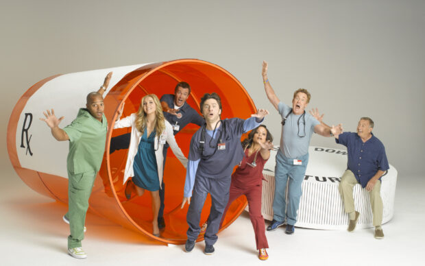 The main cast including Donald Faison poses inside a giant orange pill prop, 2K Desktop Wallpaper