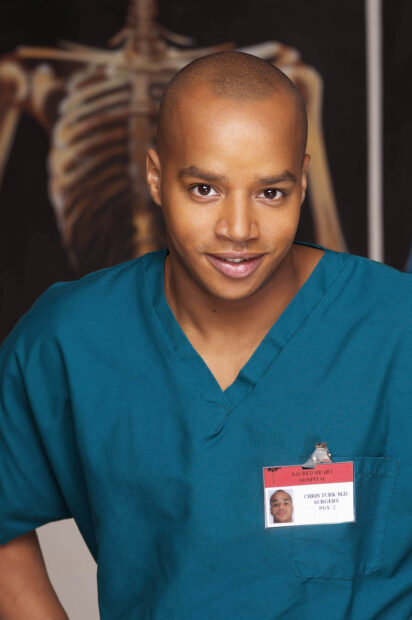 Donald Faison smiles wearing teal scrubs with a hospital ID badge, 2K Desktop Wallpaper