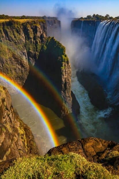 A breathtaking view of a double rainbow forming above the Devils Pool in Zambia, 2K Phone Wallpaper