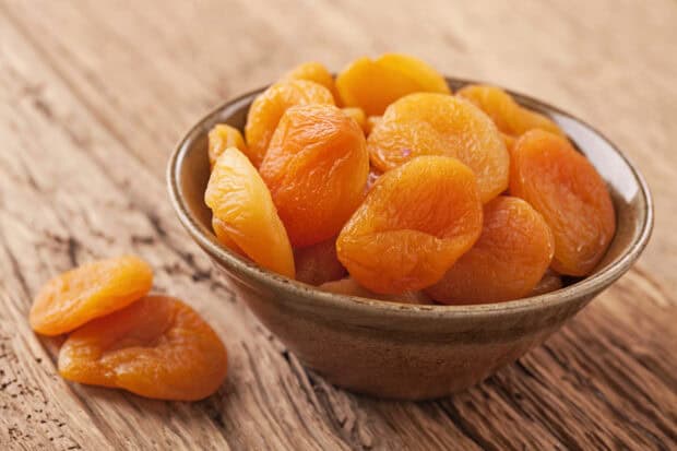 A bowl filled with dried apricots placed on a wooden surface, HD Desktop Wallpaper