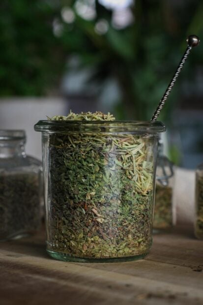A glass jar filled with dried herbs and seasoning with a spoon inside, HD Mobile Wallpaper