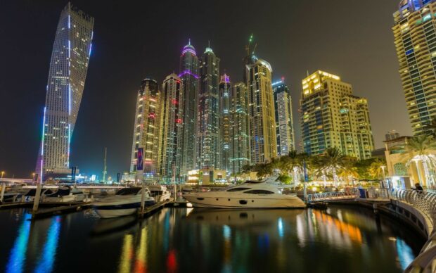 The Dubai Marina skyline reflects on the calm water with luxury yachts docked nearby, HD Desktop Wallpaper