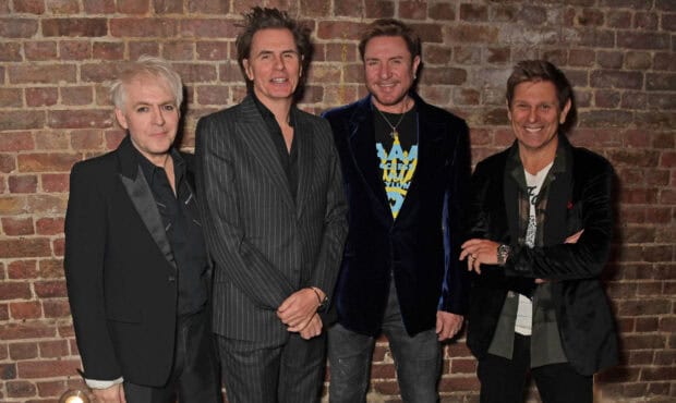 The Duran Duran members stand together in front of a brick wall smiling, HD Desktop Wallpaper