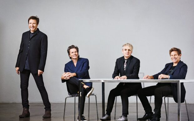 The Duran Duran group is dressed in stylish suits in a studio setting, HD Desktop Wallpaper
