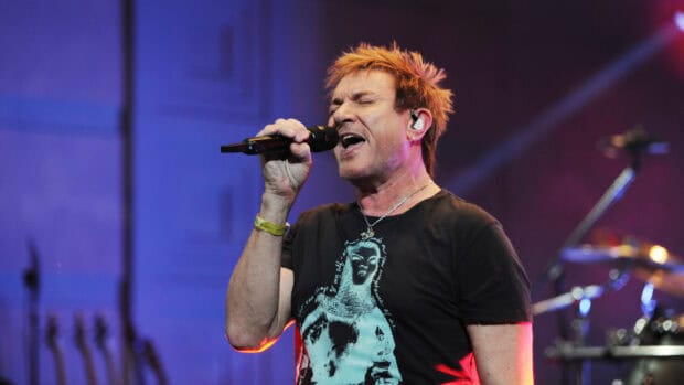 A passionate Duran Duran singer is captured mid performance on stage with vibrant lighting, 2K Desktop Wallpaper