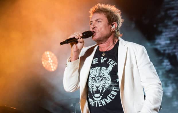 The lead singer is performing passionately on stage in front of vibrant lighting during a concert of Duran Duran wallpapers, HD Desktop Wallpaper