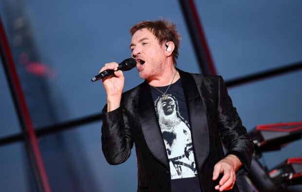 A lead singer of Duran Duran is passionately singing on stage during a concert, HD Desktop Wallpaper