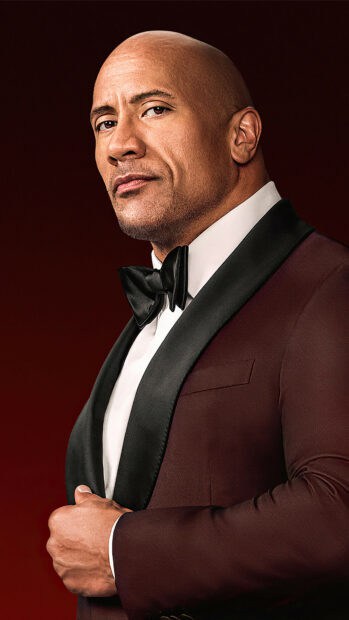 Dwayne Johnson poses confidently in a dark tuxedo against a rich red background, 4K Phone Wallpaper