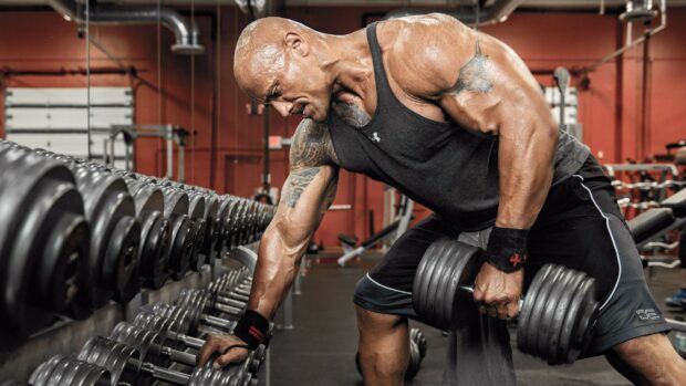Dwayne Johnson lifting heavy dumbbells during an intense gym workout, 2K Desktop Wallpaper