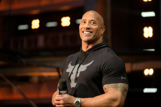 Dwayne Johnson is smiling warmly while holding a microphone during a public event, 2K Desktop Wallpaper