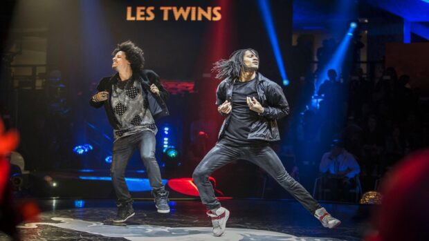Les Twins dance energetically on stage with colorful lights behind them, 2K Desktop Wallpaper