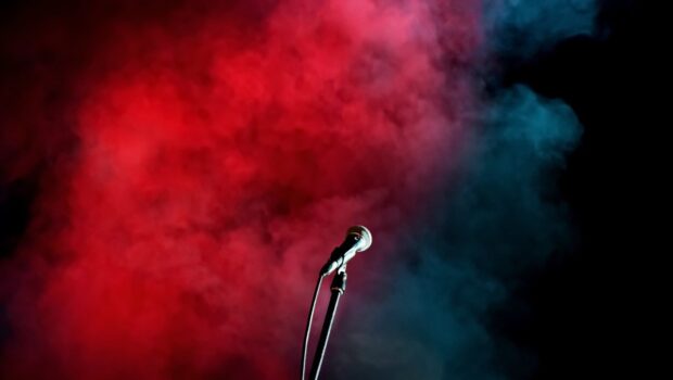 A dynamic microphone stands against vibrant red and blue smoke in a dark background, HD Desktop Wallpaper