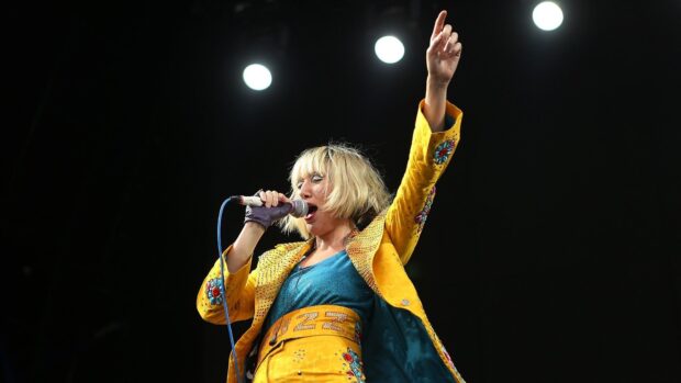 The Yeah Yeah Yeahs lead singer is performing energetically on stage with a bright outfit, HD Desktop Wallpaper