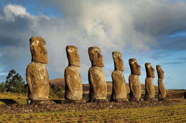 The Easter Island statues stand in a row on a grassy field under a cloudy sky, HD Desktop Wallpaper