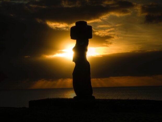 A moai statue silhouetted against a golden sunset over the ocean on Easter Island, HD Desktop Wallpaper