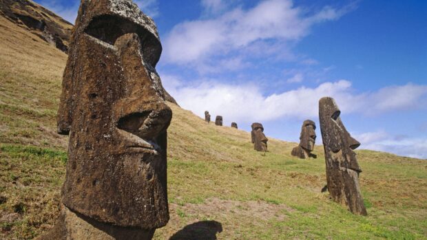 The Easter Island statues stand prominently on a green hillside under a clear blue sky, HD Desktop Wallpaper