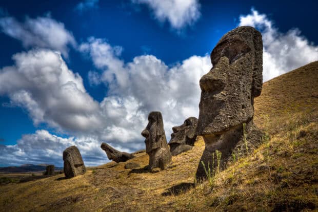 The Easter Island statues stand tall on a grassy hill under a cloudy blue sky, HD Desktop Wallpaper