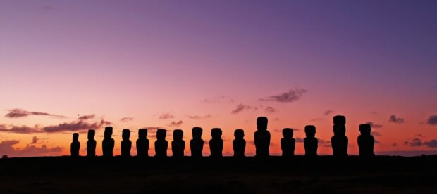 The Easter Island statues stand silhouetted against a colorful sunset sky, 2K Desktop Wallpaper