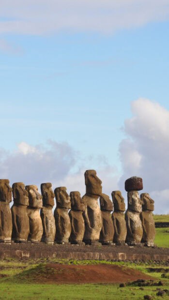 A row of Easter Island statues stands on a grassy field under a blue sky with clouds, HD Mobile Wallpaper