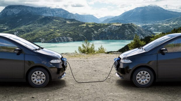 Two Sono Motors cars are connected by a charging cable near a lake and mountains, 2K Desktop Wallpaper