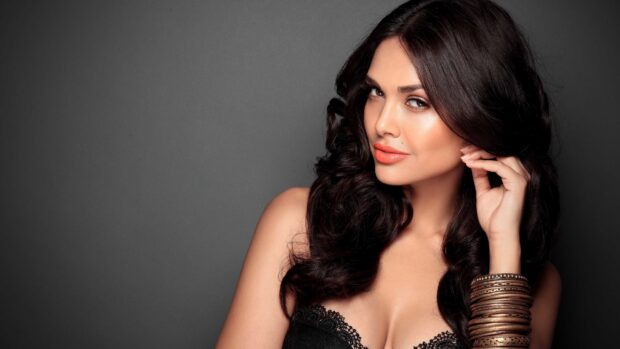 A glamorous Bollywood Wallpapers model with dark curly hair near a grey background, 4K Desktop Wallpaper