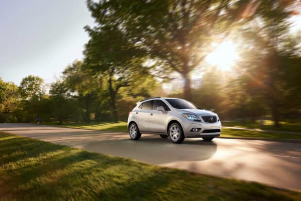 A white Buick Encore drives along a tree lined path with sunlight shining through, 2K Desktop Wallpaper