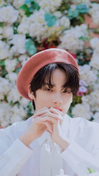 Huening Kai Wallpapers features a young man wearing a pink beret with a soft floral background, HD Mobile Wallpaper
