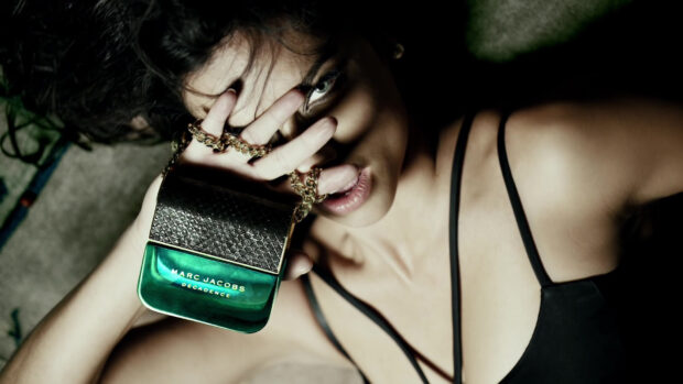 A woman holds a Marc Jacobs Decadence bottle with a gold chain close to her face, HD Desktop Wallpaper