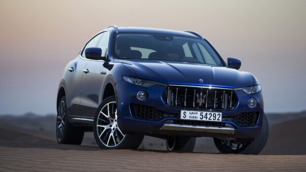 A blue Maserati Levante is parked on sand dunes with a clear sky background, HD Desktop Wallpaper