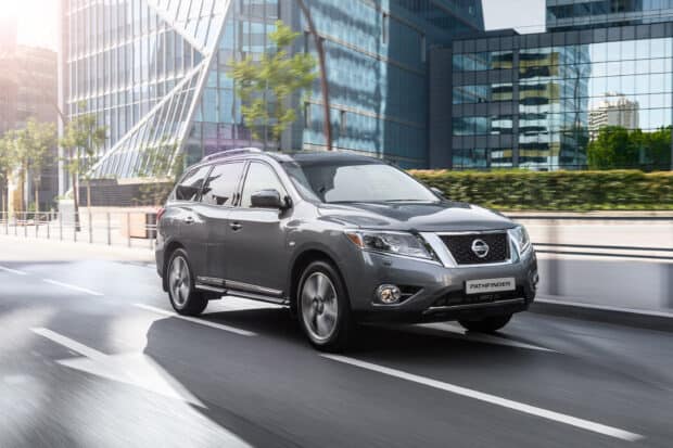 A gray Nissan Pathfinder drives on a city street with modern buildings in the background, 2K Desktop Wallpaper