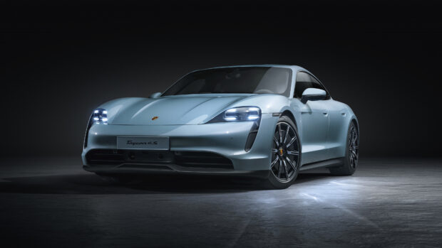 A sleek Porsche Taycan with illuminated headlights in a studio setting, 4K Desktop Wallpaper