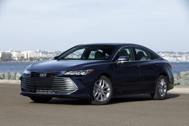 Toyota Avalon is shown in a side view by the water with city skyline, HD Desktop Wallpaper